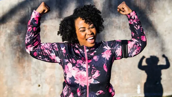 Happy woman doing a strong arm pose after an outdoor workout