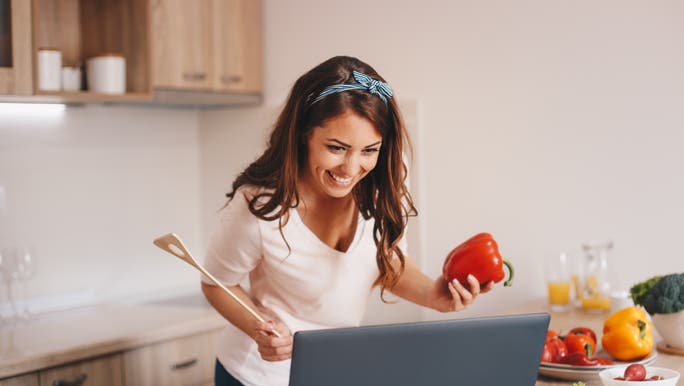 Woman in the kitchen following a recipe on her laptop