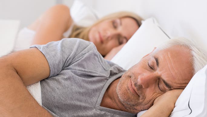 A middle-aged man and woman are sleeping together