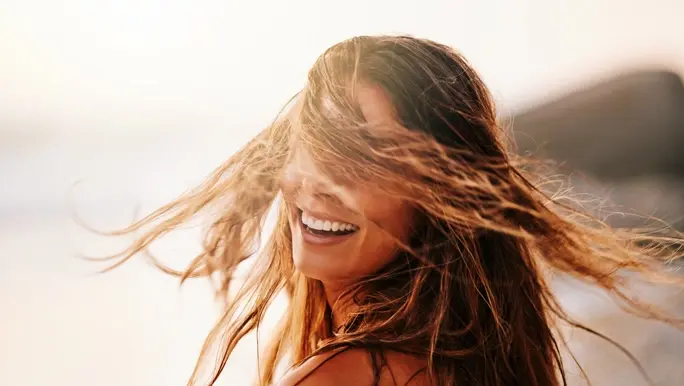 Carefree woman laughing and swinging her hair around at the beach