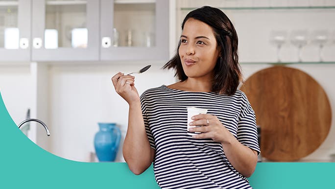 Woman in the kitchen snacking on yoghurt