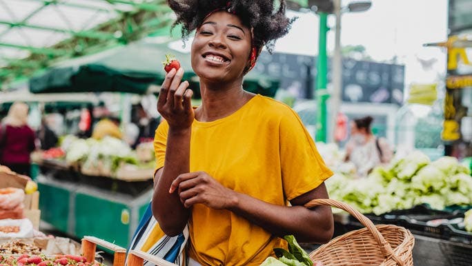 Happy woman shopping for strawberries at the local farmer's market
