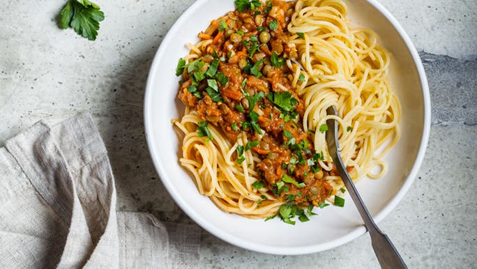 A bowl of vegan lentil bolognese sauce with pasta that has lentils as vegan protein substitutes for meat. 