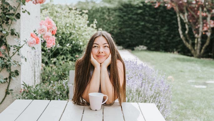 Relaxed young woman enjoying a cup of tea in the rose garden