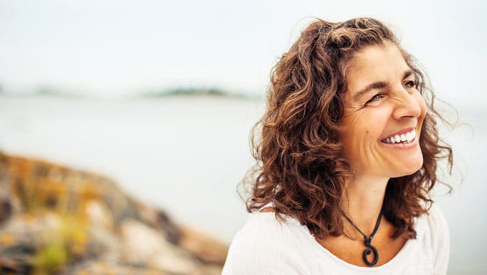 Happy, beautiful mature woman outside by the ocean