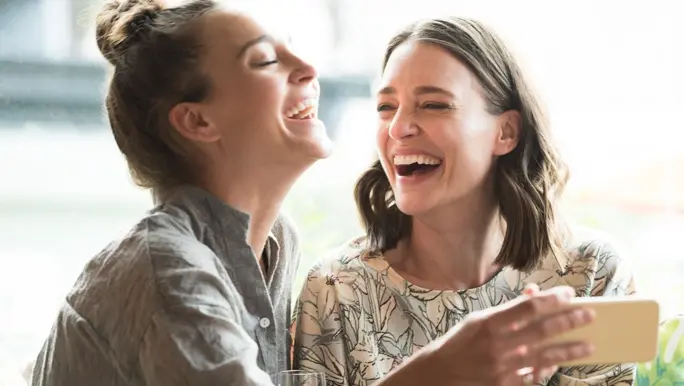 Two female friends laughing and taking a selfie on Galentine's Day