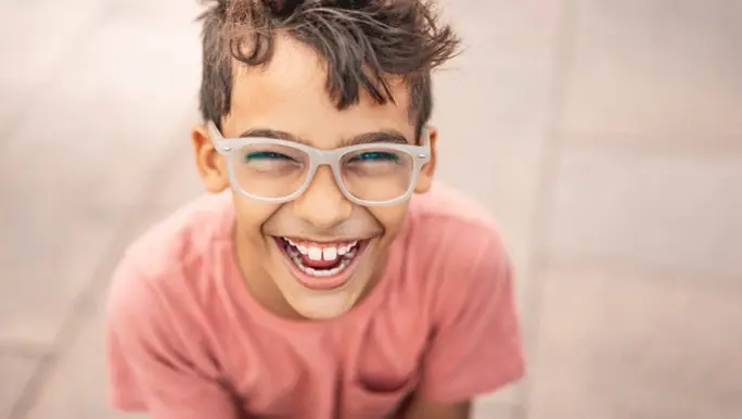 Happy laughing boy in a pink t-shirt and glasses