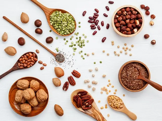 Various legumes and different kinds of nuts walnuts kernels ,hazelnuts, almond kernels,brown pinto ,soy beans ,flax seeds ,chia ,red kidney beans and pecan set up on white wooden table