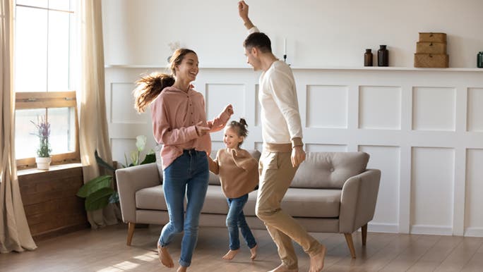 A family dances in their home happily, productivity hacks have changed their lives. 