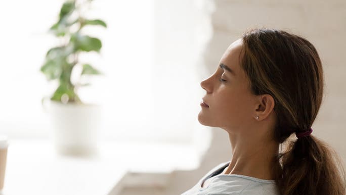From the side, a woman is sitting with her eyes closed practising mindfulness for her nervous system, which can increase libido.
