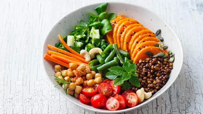 Healthy vegetarian salad. Lentil, chickpea, carrot, pumpkin, tomatoes, cucumber, lettuce.