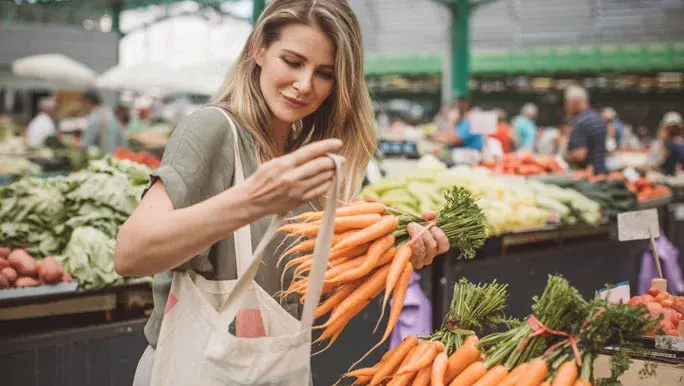 Woman buying carrots at the farmers markets