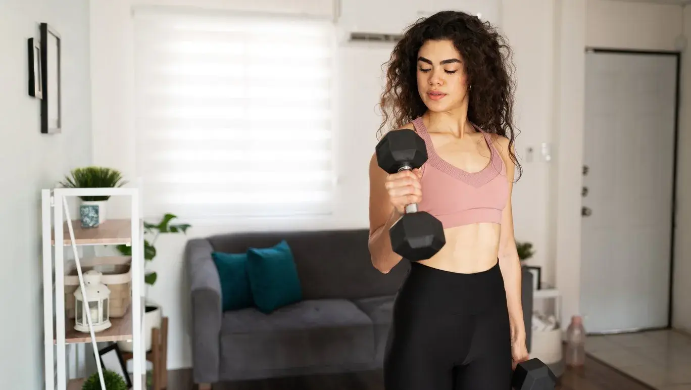 Young woman lifting weights in her living room
