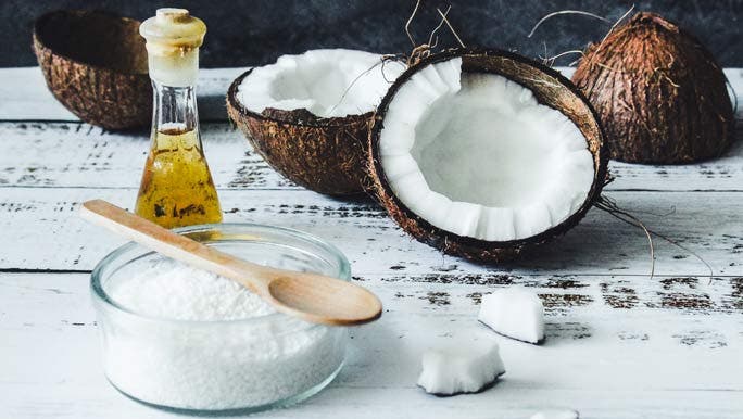 Coconut halves, desiccated coconut and coconut oil on a timber bench top