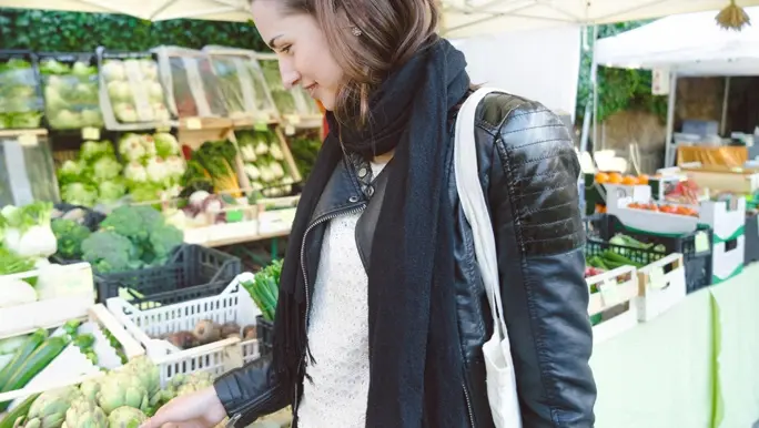 Woman at the market buying prebiotic globe artichokes