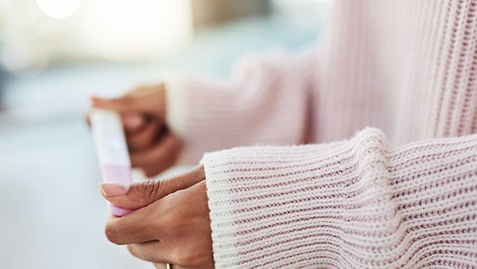 Two hands hold a pregnancy test - it’s unclear if it’s negative or positive.