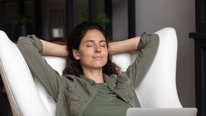 A lady is napping on a cozy chair, while she is in front of her laptop. This is one way to feel better after a bad day.