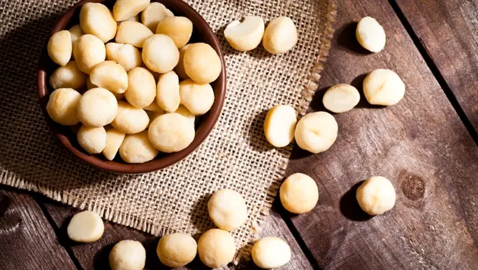 Raw macadamia nuts in a wooden bowl
