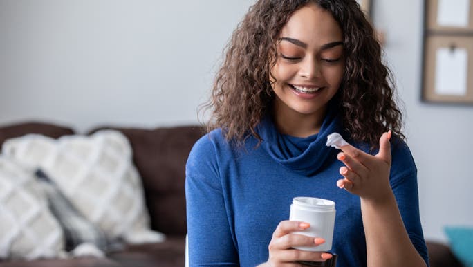 Woman in a blue top moisturising her hands