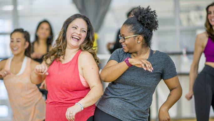A group of women do fun exercise in a gym, happy about how long it takes to see gym results.
