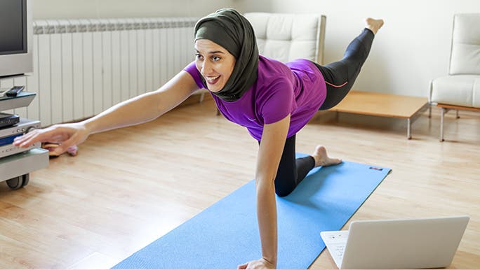 A woman is doing an exercise to build core strength in her home. 