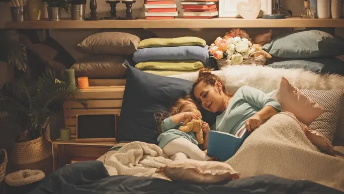 Mum and daughter tucked up in bed reading a book