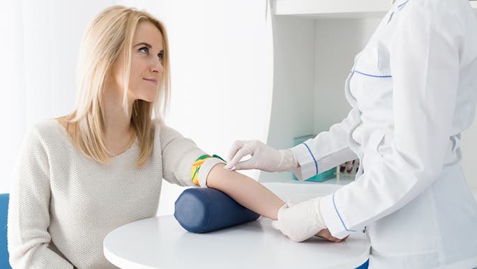 Young blonde woman in a white jumper having a blood test, which is a way to check for signs of ovulation during IVF