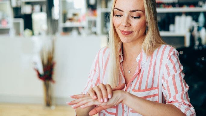 A young woman is smiling and inspecting her nails