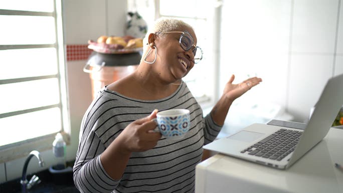 A woman smiles while looking at a meeting on her laptop as she has learned how to say no politely. 