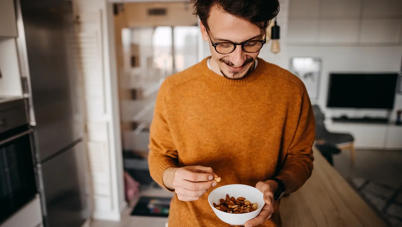 happy and healthy young man holding a bowl full of nuts