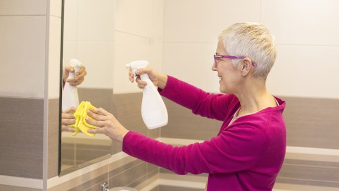 While cleaning the mirror in her bathroom, a woman is thinking about learning some cleaning window hacks. 