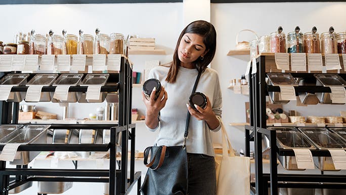 Woman in wholefoods store weighing up the pros and cons of organic food.