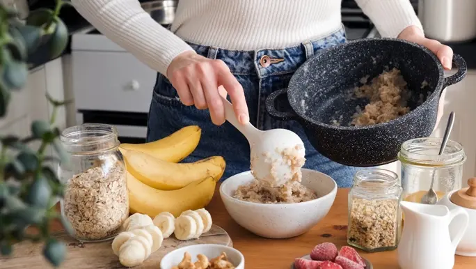 Woman make oat porridge for breakfast with banana, berries and low FODMAP nuts