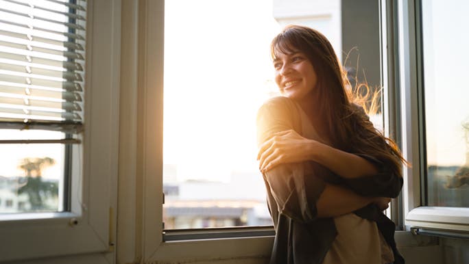  woman with crossed arms smiles as she repeats her daily positive affirmations.