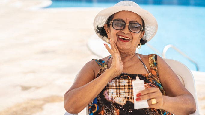 Mature woman poolside applying SPF 50