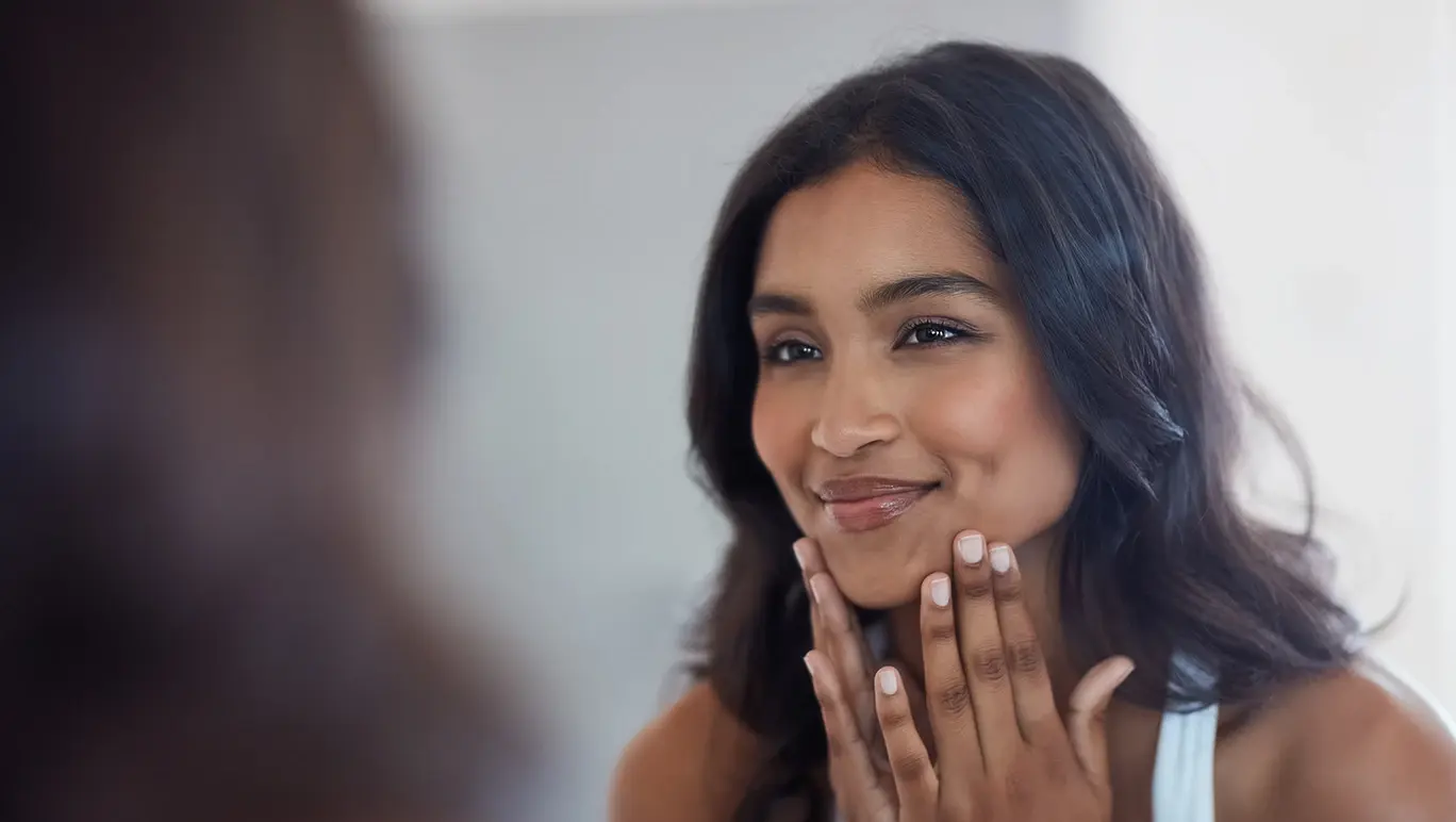 Shot of a beautiful young woman admiring herself in the mirror at home.