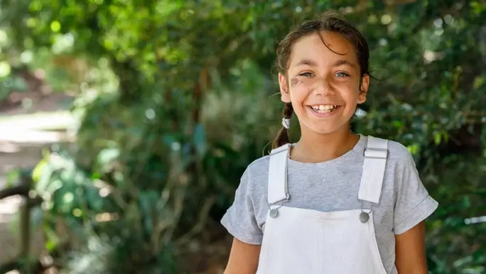 Happy smiling tween girl in overalls and t-shirt