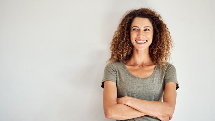 Happy and confident woman standing against a grey wall