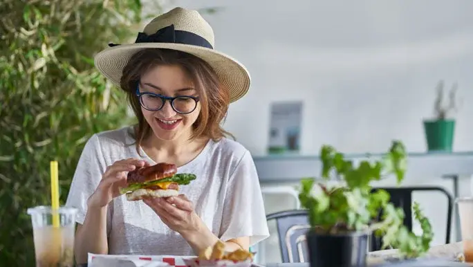 Smiling young woman eating a vegan burger