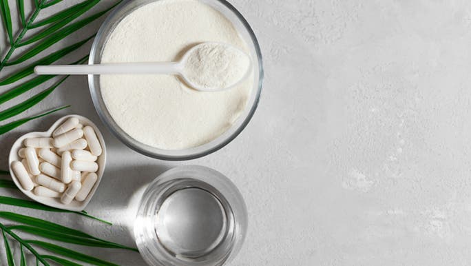 Collagen supplements in a white powder form in a glass bowl and white capsules in a heart-shaped bowl