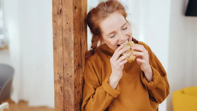 Red headed woman enjoying a sandwich made with wholegrain bread