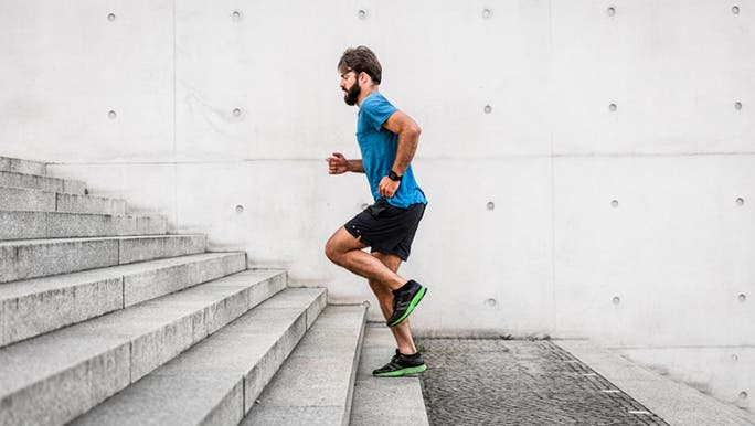 A white Caucasian male wearing a blue T-shirt is running up a set of stairs, which may be considered a good form of exercise for male fertility
