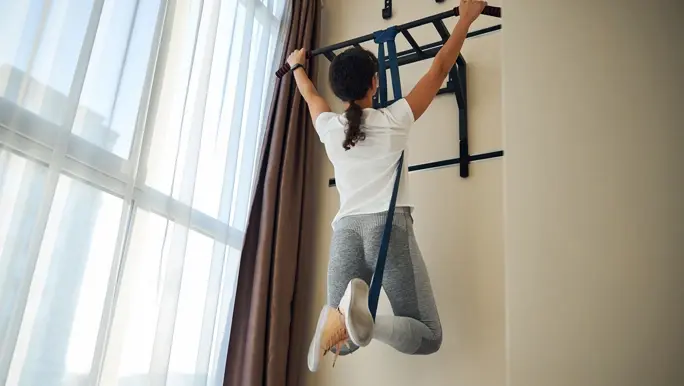 Brunette woman doing a pull up at home using a resistance band