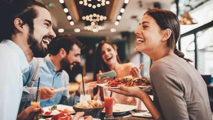Four happy friends sharing a meal in a restaurant