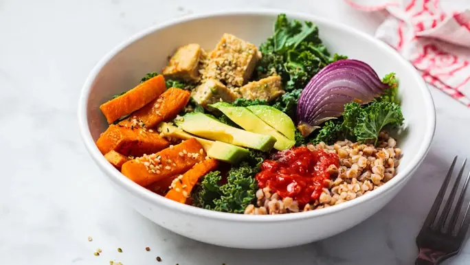 Vegan buddha bowl with tofu, buckwheat, kale, carrots, red onion and avocado