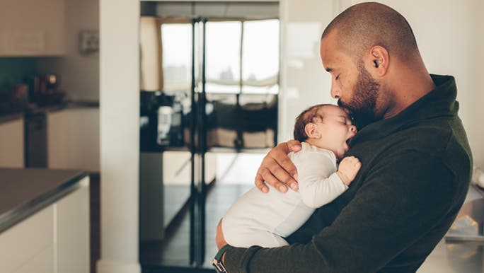 A father kisses his young baby wondering why newborns have hiccups so often.