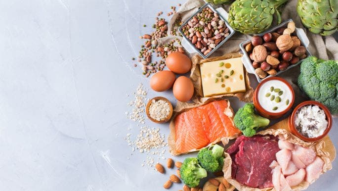 A flat lay image of protein sources including meat, fish, cheese, nuts, legumes and yoghurt
