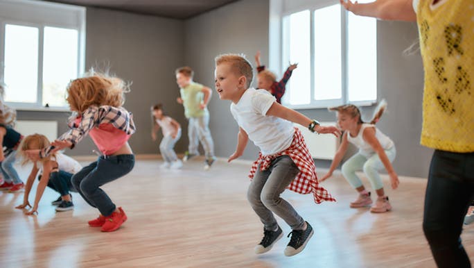 An action shot of children jumping in the air in an exercise class for kids. 