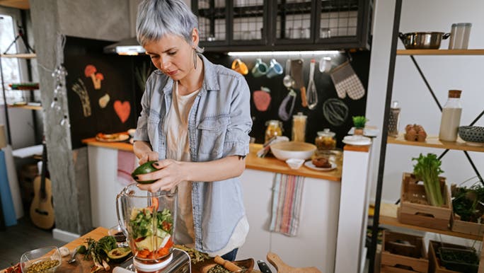 A woman blends vegetables, perhaps as part of trying to detox her liver