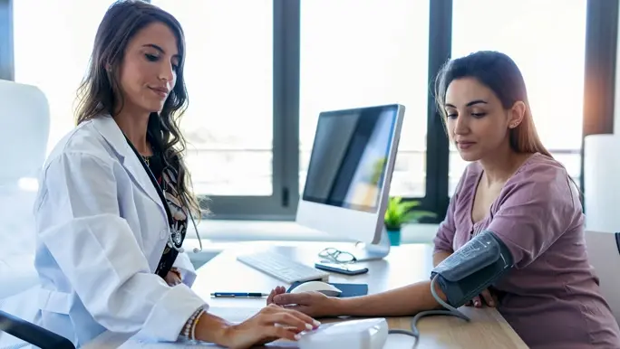 A woman having her blood pressure measured by her doctor